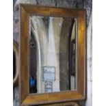 A contemporary gilt framed wall mirror of rectangular form with bevelled edge plate and foliate