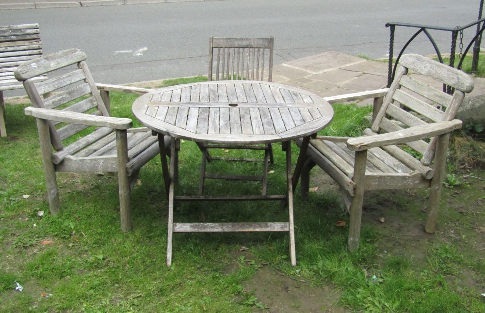 A weathered teak folding garden table of circular form with slatted top, together with a Royal Craft