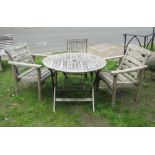 A weathered teak folding garden table of circular form with slatted top, together with a Royal Craft