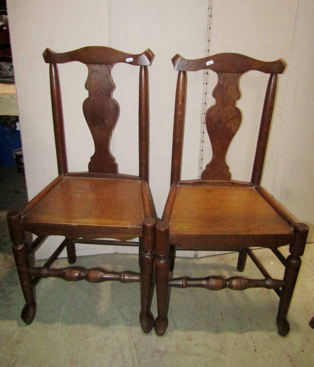 A pair of Georgian oak dining chairs with yoke shaped rails, vase shaped splats, solid seats