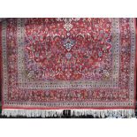 Good quality Persian carpet with intricate scrolled floral decoration upon a rich red ground, 330