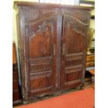 A small 18th century Flemish fruitwood armoire enclosed by a pair of shaped and panelled doors, with