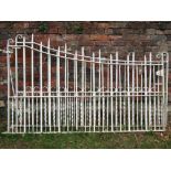 A pair of heavy cream painted ironwork driveway entrance gates, with vertical rails, spiral and