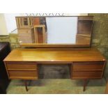 A teak Austin suite kneehole dressing table fitted with four drawers and raised on simple turned