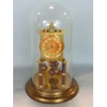 Brass 400 day anniversary clock under a glass dome, with orange sunburst dial and brass chapter ring