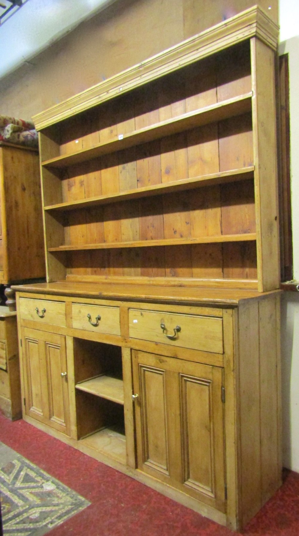 A vintage stripped pine kitchen dresser, the base enclosed by a pair of twin moulded rectangular