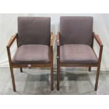 A pair of retro teak framed open armchairs with upholstered seats and backs raised on simple
