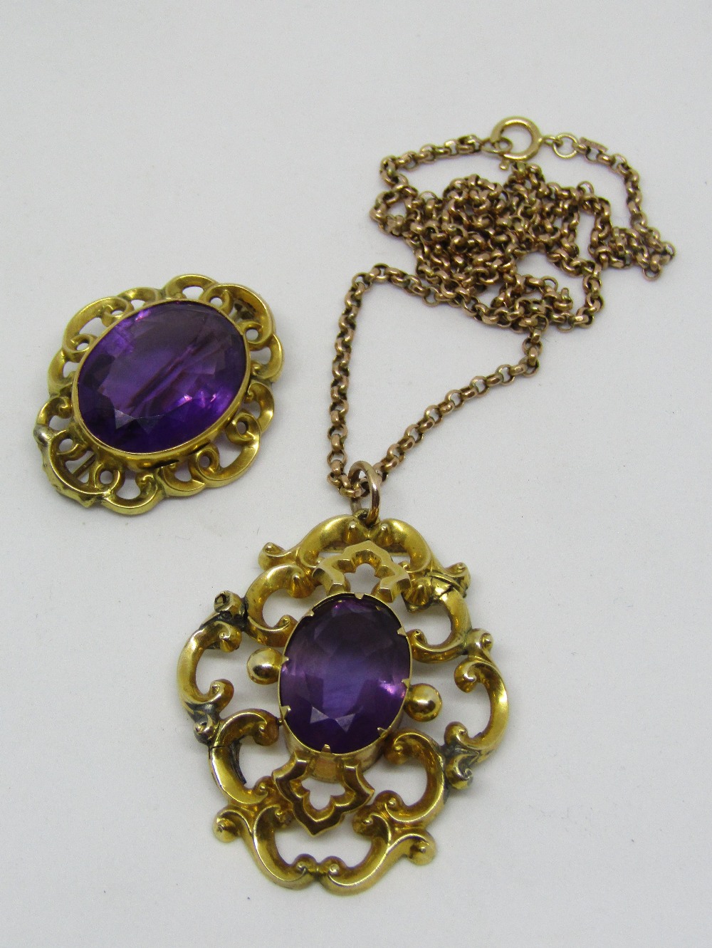 Victorian amethyst and yellow metal brooch with scrolled mount, together with a similar pendant hung