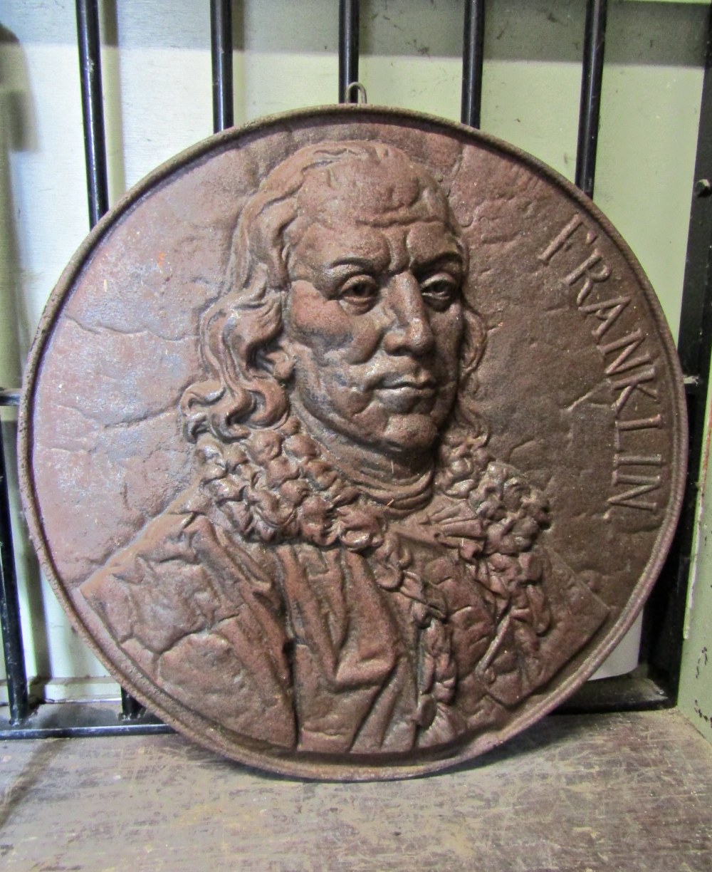 A cast iron circular walk plaque with raised head and shoulder relief of Benjamin Franklin, 54cm