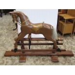 A traditional wooden rocking horse with brown painted colourway, raised on a stand, 103cm high
