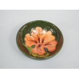 A green ground Moorcroft Hibiscus pattern bowl with impressed mark to base, 9.5cm diameter