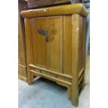A Japanese pine cabinet of tapering form enclosed by a pair of panelled doors over two frieze