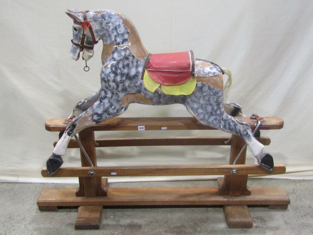 A vintage traditional wooden rocking horse with dapple grey painted finish, raised on a pine and