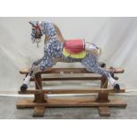 A vintage traditional wooden rocking horse with dapple grey painted finish, raised on a pine and