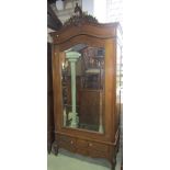 An oak armoire, the moulded arched cornice with carved pediment over a three quarter length bevelled