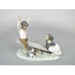 A Lladro model of children playing on a see saw, 23.5 cms long approx