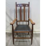 An arts and crafts oak open elbow chair with pierced cresting rail over a faux leather pad seat,