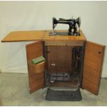 A vintage oak cased Singer treadle sewing machine enclosed by two doors and folding top