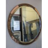 An art deco style wall mirror of circular form with alternating peach tinted glass surround