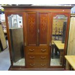 An inlaid Edwardian mahogany triple compactum wardrobe, the central section fitted with three long