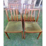 A set of four teak framed dining chairs, with curved and moulded lathe backs over upholstered