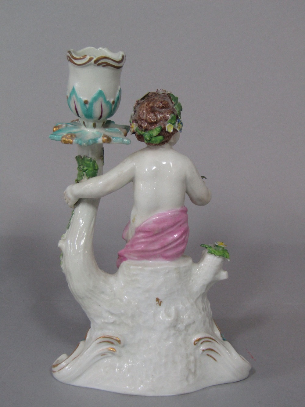 A candlestick in the Chelsea manner with applied figure of a cherub, with floral garland raised on a - Image 2 of 3