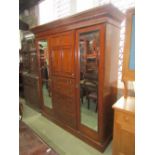 A good quality inlaid Edwardian mahogany triple compactum wardrobe enclosed by an arrangement of