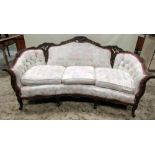 A three seat sofa with shaped outline, floral patterned and buttoned upholstery within a shaped