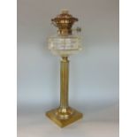 An early 19th century cast brass corinthian column oil lamp with clear glass reservoir, 46cm high