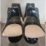 A set of four moulded grey tinted plastic swivel dining chairs, with shaped outline and