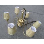 A polished brass six branch electrolier with knopped stem and pleated shades