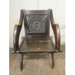A 19th century oak Glastonbury chair, the back panel with carved repeating detail and monogram