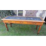 An Edwardian pitch pine and oak writing table of narrow rectangular form with moulded outline and