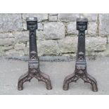 A pair of heavy 19th century cast iron andirons with Gothic tracery detail and face mask finials,