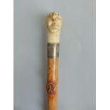 Interesting hawthorn/knobbly waling cane carved with various faces in a coiled snake, with silver