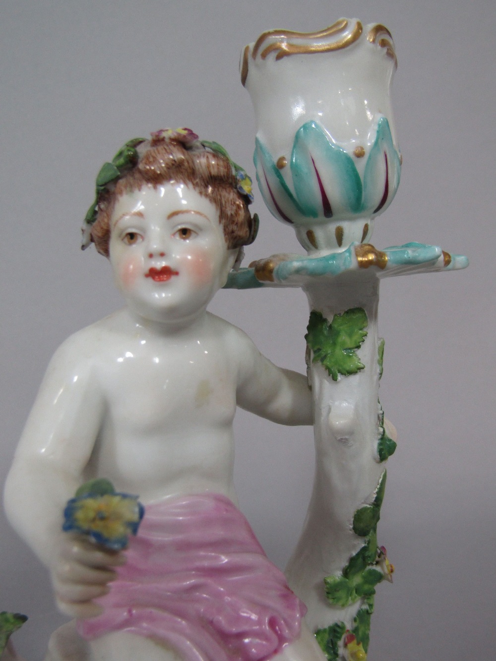 A candlestick in the Chelsea manner with applied figure of a cherub, with floral garland raised on a - Image 3 of 3