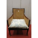 A 19th century bergere chair with down swept and mounted frame, raised on square tapered forelegs