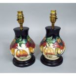 A pair of Moorcroft lamp bases with lily decoration, raised on circular bases, with electrical