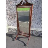 An Edwardian mahogany cheval glass enclosing a mirror plate with bevelled edge, the framework with