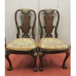 A pair of 18th century walnut side chairs, the top rails centred by a shell crest, with needlework