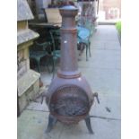 A cast iron pot bellied chiminea raised on three shaped supports