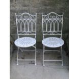 A pair of cast iron bench ends with decorative pierced foliate detail and green painted finish,