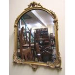A small gilt framed wall mirror of arched form with scrolling acanthus detail, 70 cm high x 50 cm