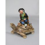 A Goldscheider box and cover in the form of a tortoise with girl in Japanese style costume riding on