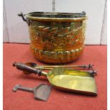 An antique embossed brass cauldron of circular form with steel loop handle, with trailing floral and