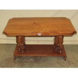 A teak wood occasional table of rectangular form with moulded corners raised on a pair of carved