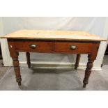 An old pine kitchen table of rectangular form fitted with two frieze drawers raised on turned
