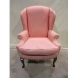 A Georgian style wing armchair with shaped outline, upholstered in pale pink geometric patterned