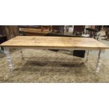 A pine farmhouse kitchen table of rectangular form, the stripped plank top raised on four turned