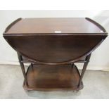 An Ercol dark stained oval drop leaf two tier tea trolley raised on shepherds castors